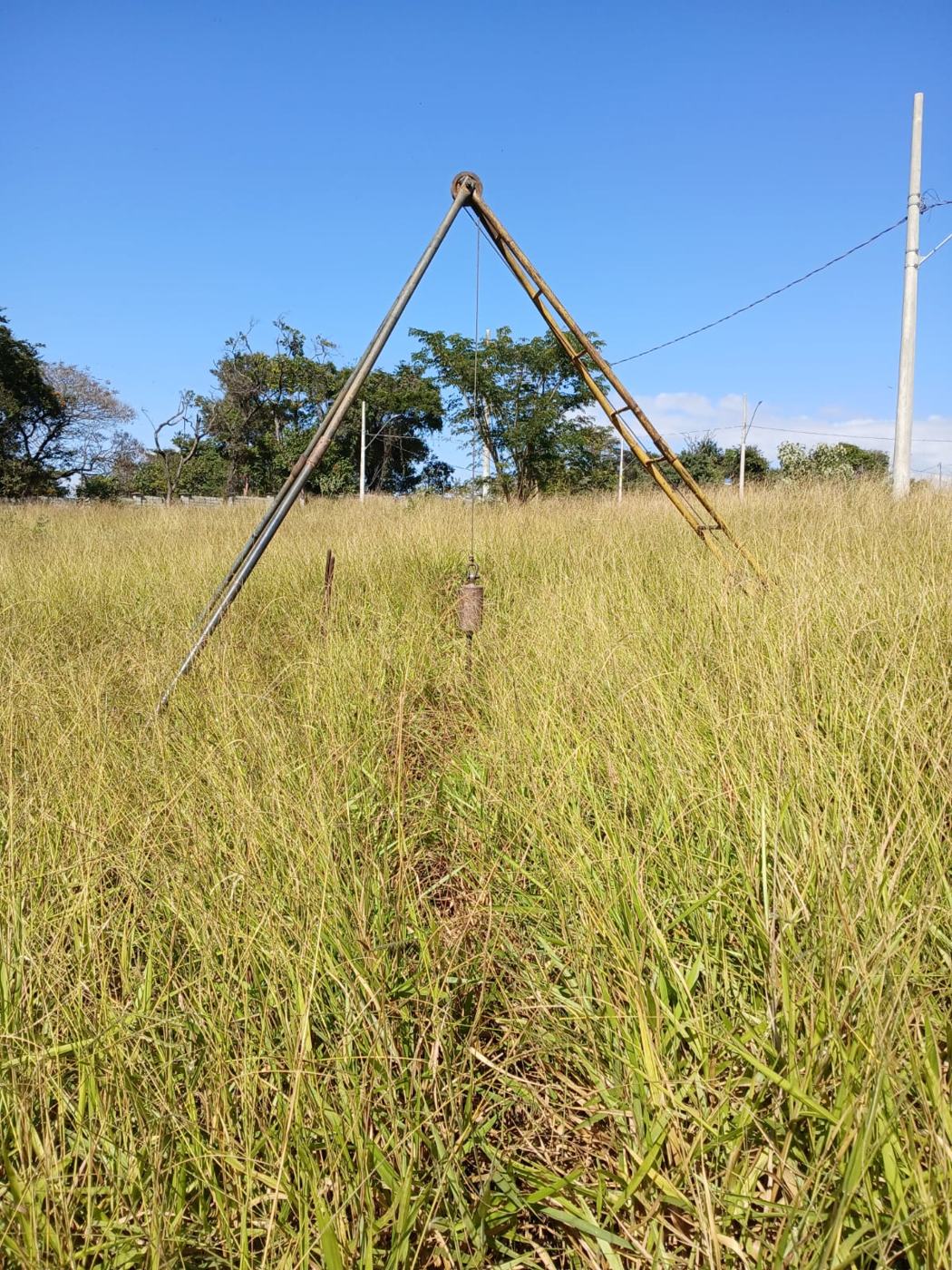Tripé de sondagem SPT montado em campo aberto, sob céu azul